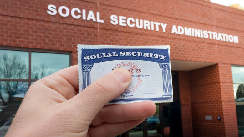 Hand holding Social Security card in front of SSA building