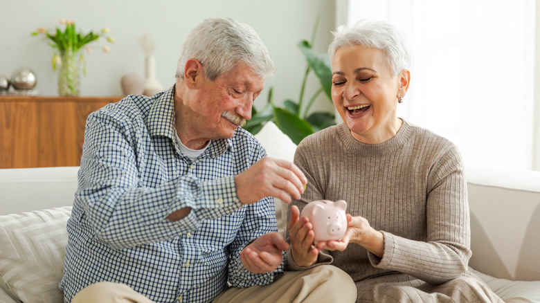 senior couple putting money in a piggy bank