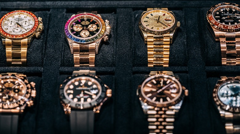 Two rows of Rolex watches for sale on display in velvet cases.