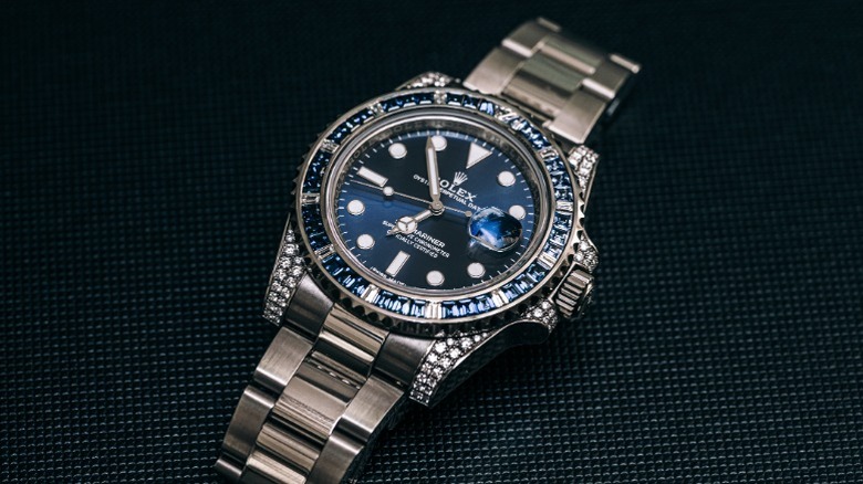 A modern Rolex Submariner watch with a blue dial and bevel laying on a dark surface.