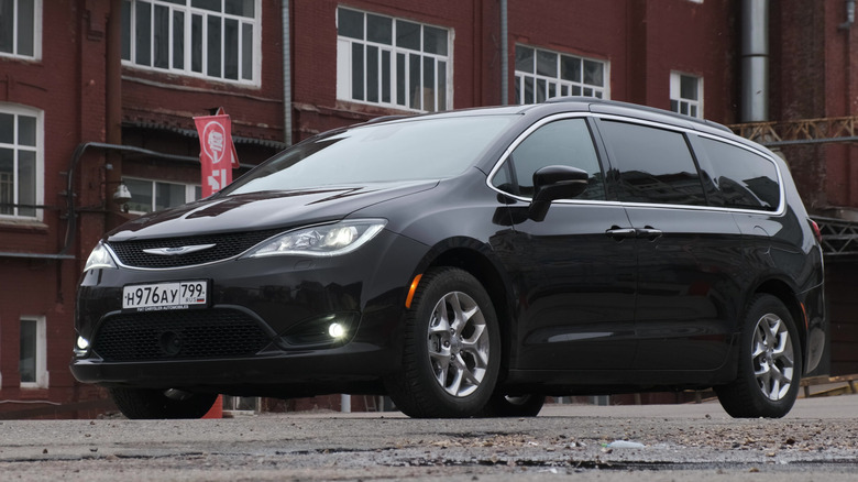 A black Chrysler Pacifica minivan parked outside next to a brick building.