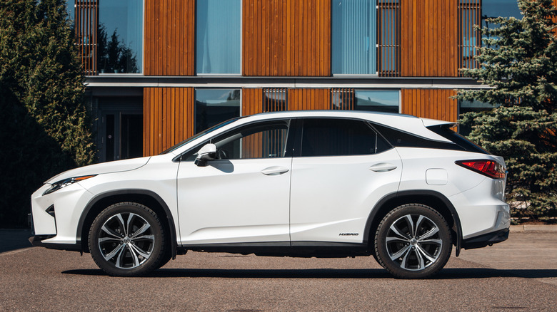 A white Lexus RX Hybrid parked outside near a building.