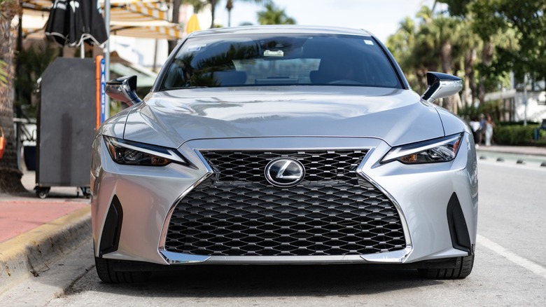 Front view of a silver Lexus IS sedan parked along a palm-lined street