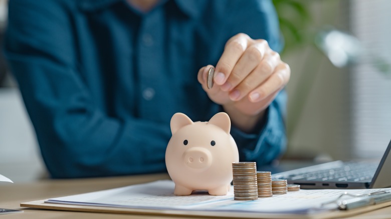 man putting money in a piggy bank