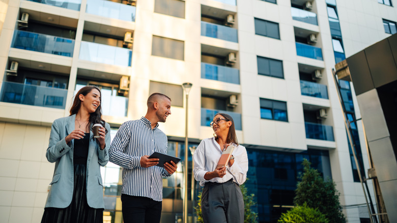 three people walking and talking in front of an apartment building