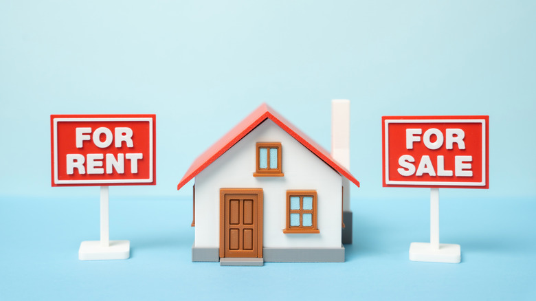 "For rent" and "For sale" signs next to house figurine