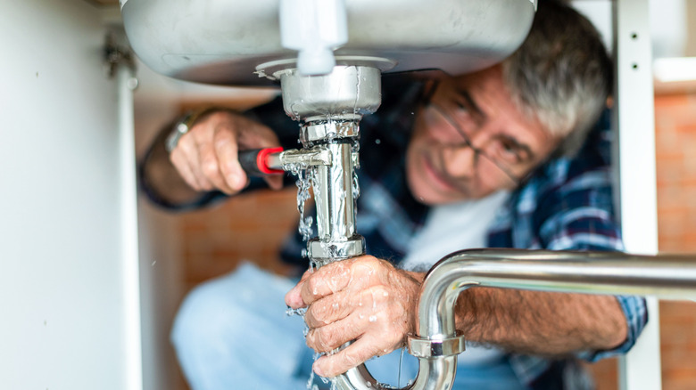An older man fixing a sink