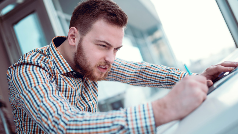 architect making a strange face while drawing hunched over a desk