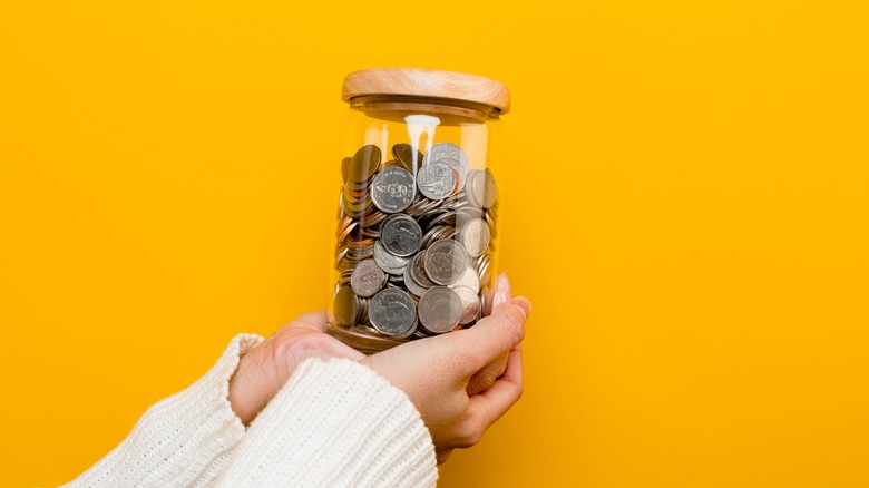 holding a jar of coins