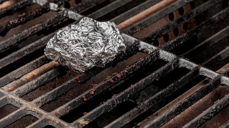 Aluminum foil on a grill with black stains on the grates