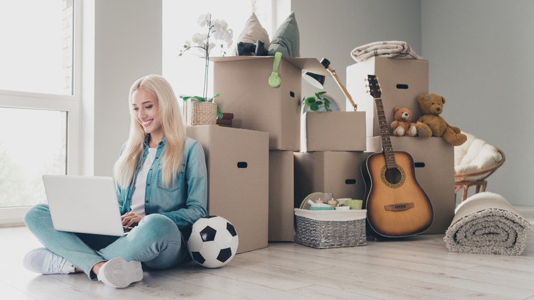 woman on a laptop in front of moving boxes