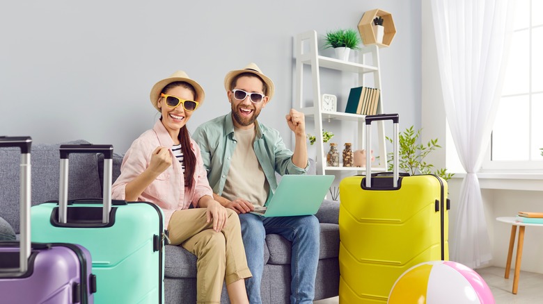 Two delighted travelers with bags packed giving a triumphant fist in the air