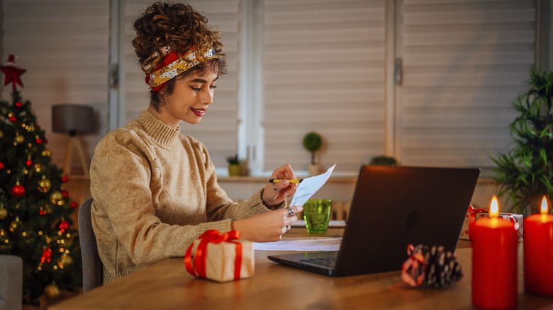 Women in front of chrstmas tree looking a credit card bill.