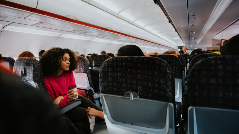 Female airline passenger in seat with cup of coffee