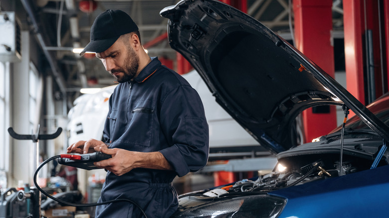 Mechanic with digital tablet working in a car service station.