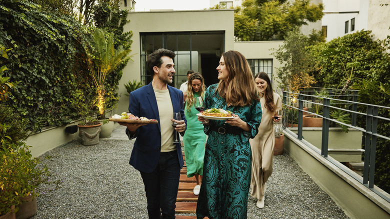 people carrying plates outside to fancy dinner at home