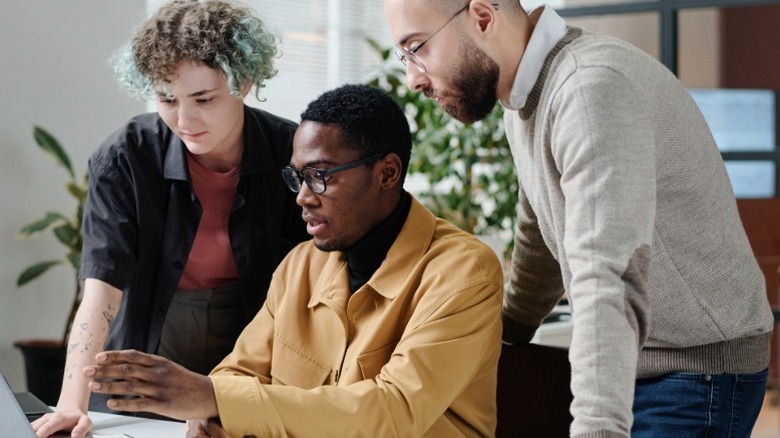 Millennial and Gen Z coworkers looking at a laptop for financial planning.