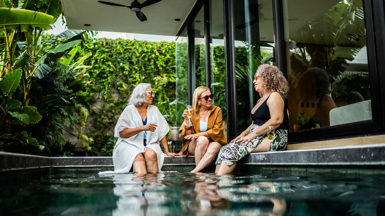 Senior friends sitting at edge of pool.