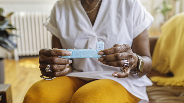 An older woman prepares to take her prescriptions for the day