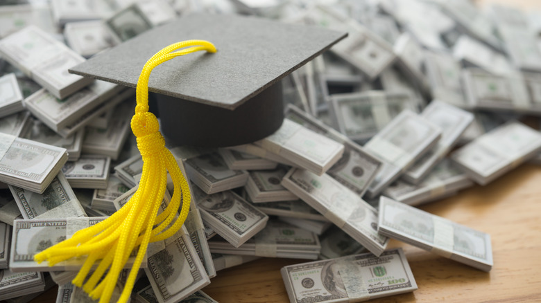 A miniature graduation cap sitting on top of money