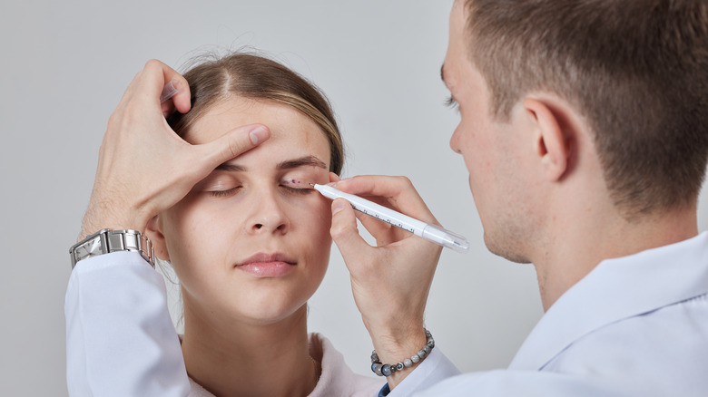Plastic surgeon prepares patient for procedure.