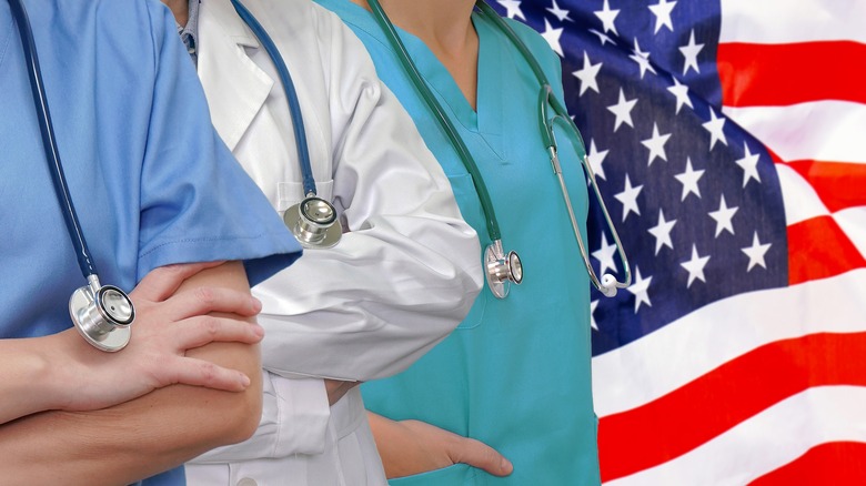 Medical professionals stand in front of United States flag.
