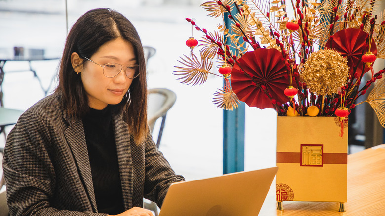 Woman at a laptop with flower arrangement next to her