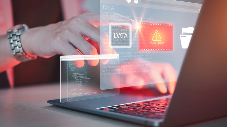 Person operating computer with a systems hacked warning