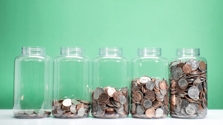 glass jars containing different amounts of coins