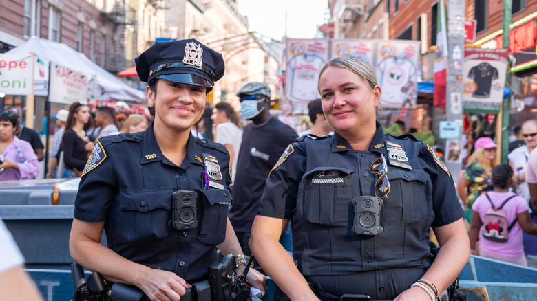 Two smiling NYPD officers pose for the camera in their uniforms,