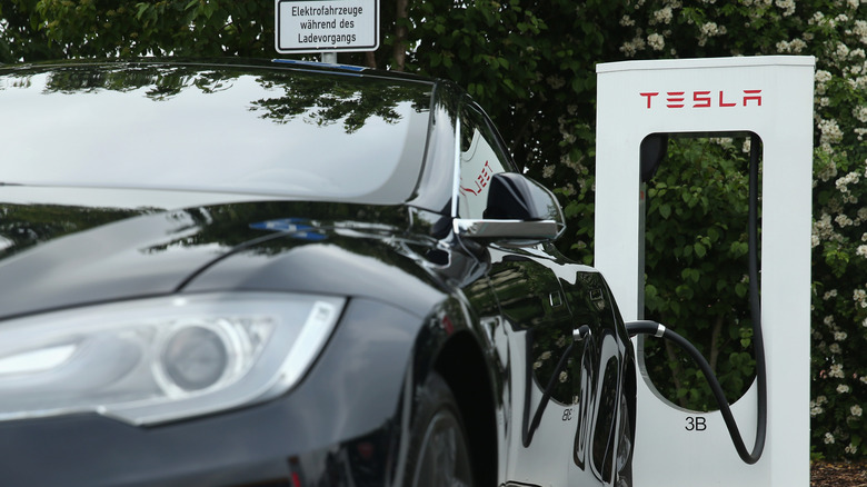 Tesla electric-powered sedan stands at a Tesla charging station at a highway rest stop along the A7 highway