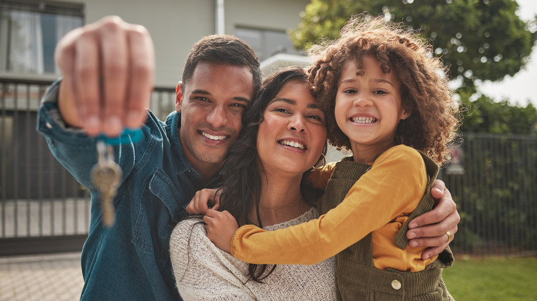 Happy looking family holding up keys to new home
