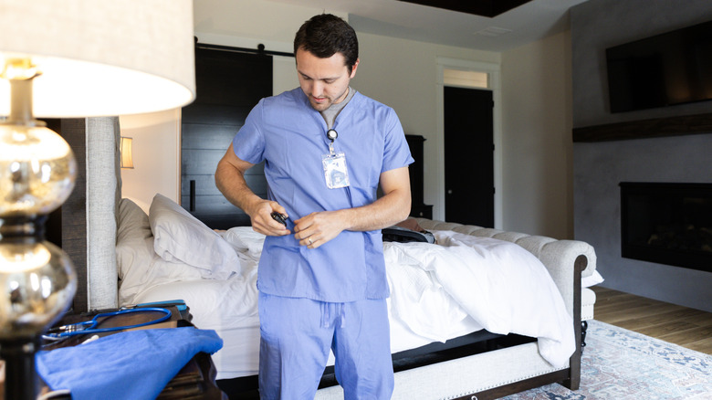 Person in medical scrubs checks pager.