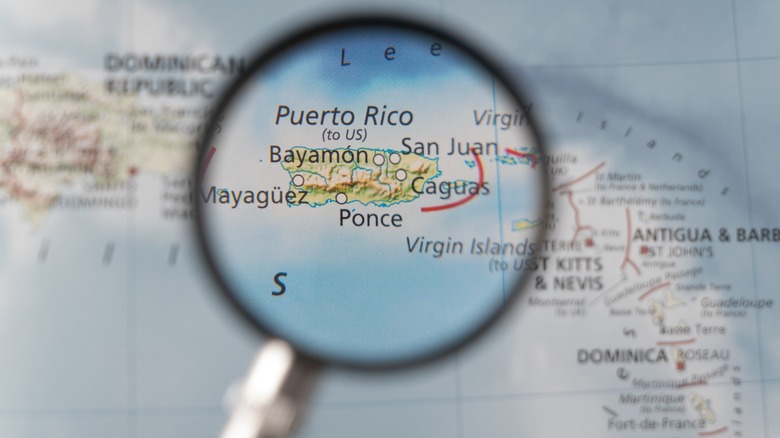 Magnifying glass zoomed in on Puerto Rico on a map, with nearby Caribbean islands slightly blurred