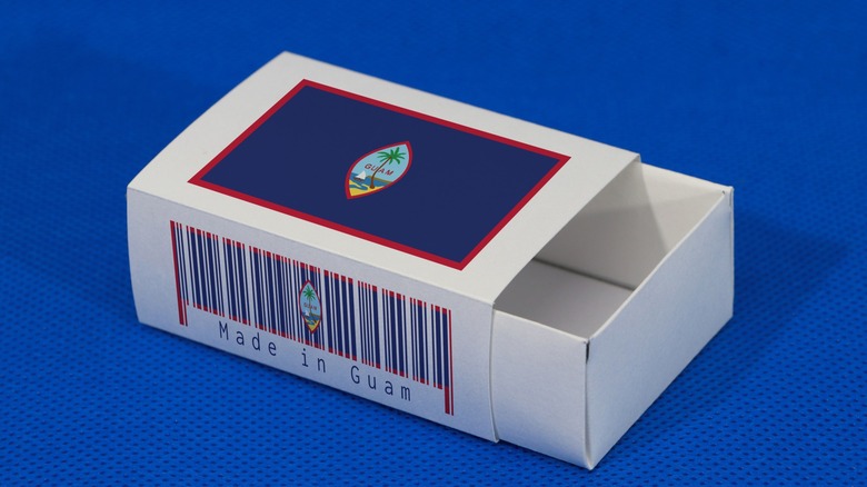 A small white matchbox with Guam's flag on the lid and a 'Made in Guam' barcode on the front