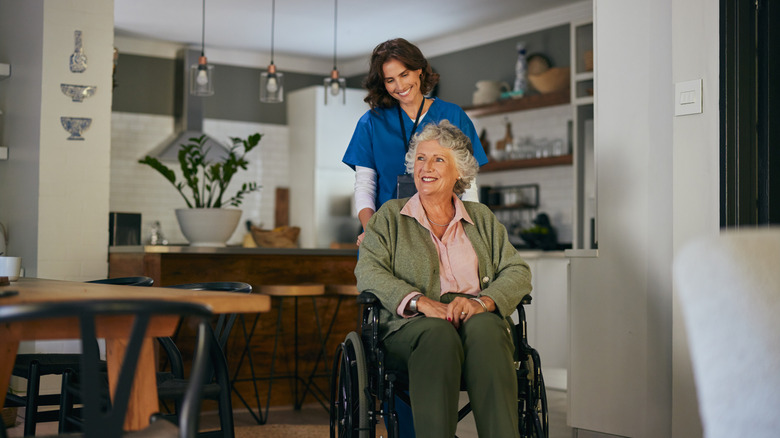 Elderly woman i wheelchair being pushed by health aid