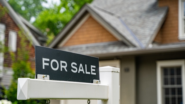 A real estate for sale sign outside of a home.