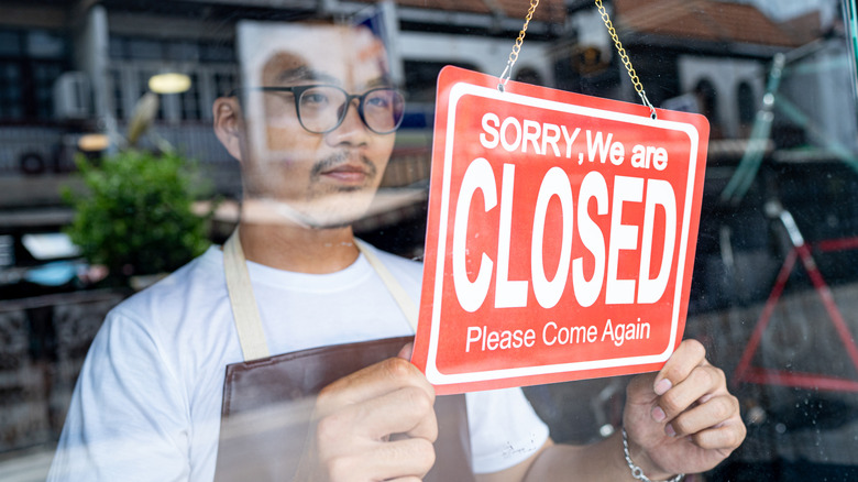 Business owner hanging closed sign in front of shop