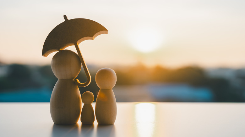 Family figures under an umbrella.