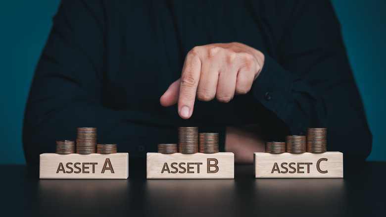 photo of coins stacked in threes over three wooden blocks marked asset a, asset b and asset c