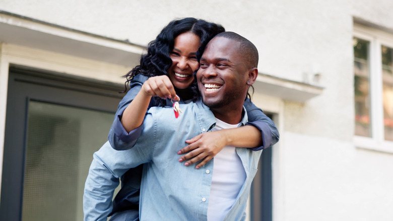 A young couple smiling holding the keys to their new home