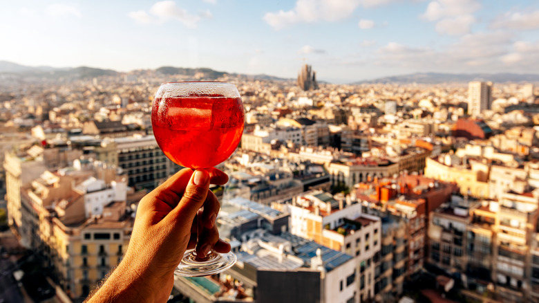 Woman holding up glass of sangria with the Barcelona skyline in the background