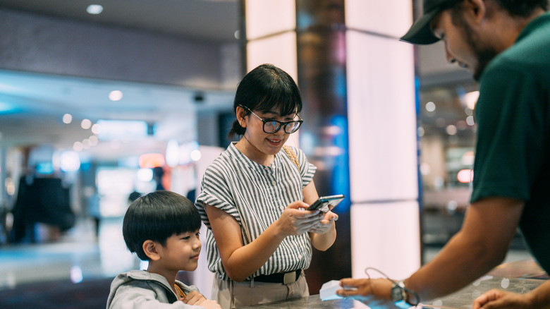 Mother and son purchase a movie ticket at box office