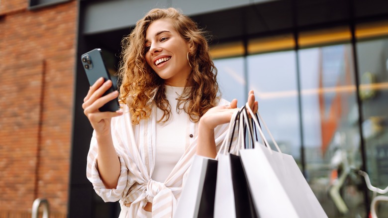 Young woman shopping and checking her phone