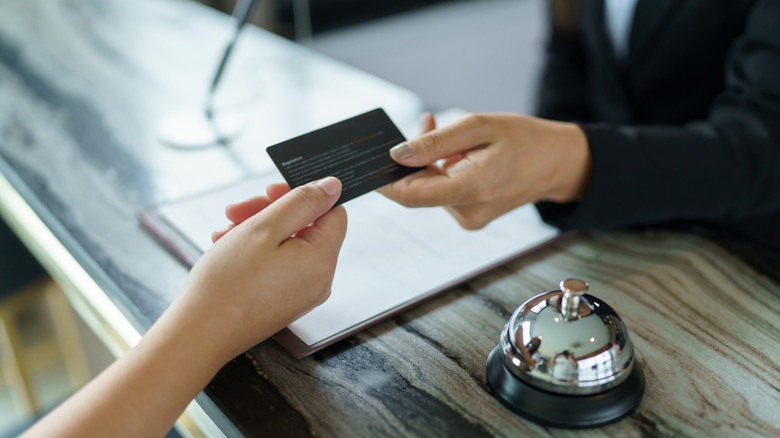 Hands holding a credit card at hotel front desk
