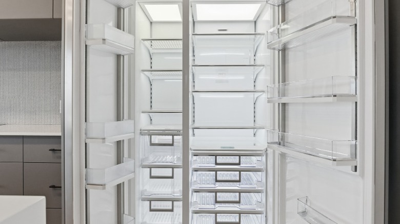 A brand-new refrigerator with both doors open showing empty shelves.
