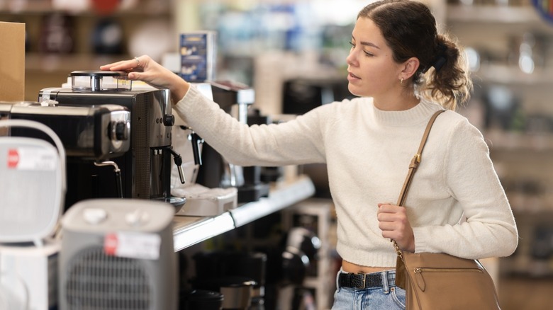 A young woman shopping for appliances at a store.
