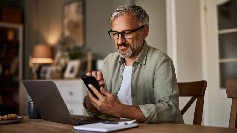 Older man with a laptop and a cell phone