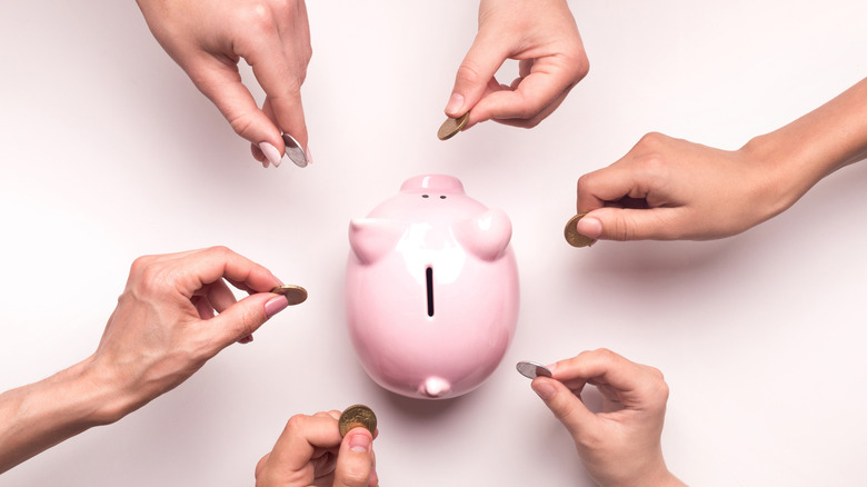 People hands throwing coins in piggy bank for crowdfunding