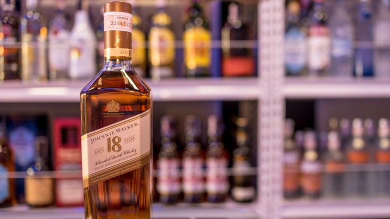 Bottle of Johnnie Walker in front of shelves of liquor
